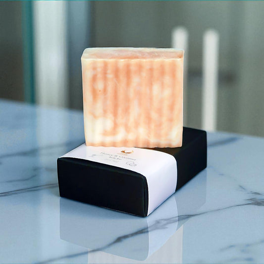 Handcrafted honey & coconut soap bar displayed on a sleek black box, showcasing its creamy texture and natural ingredients.