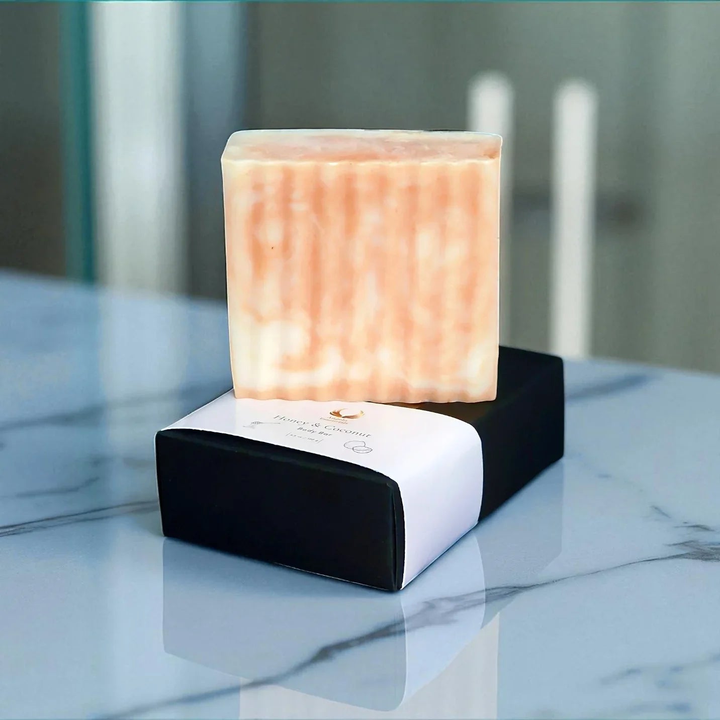 Handcrafted honey & coconut soap bar displayed on a sleek black box, showcasing its creamy texture and natural ingredients.