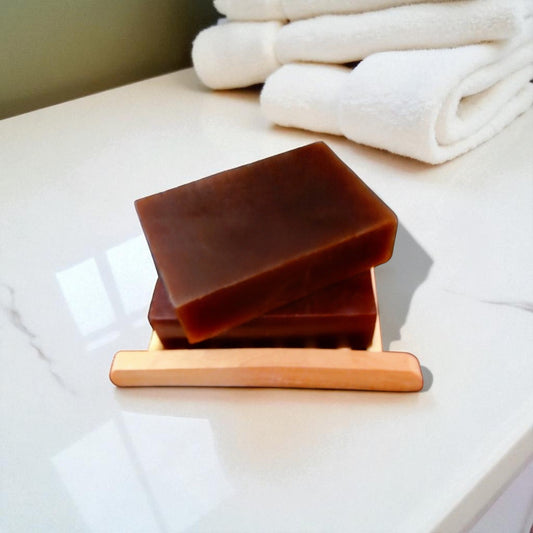 Neem Aloe Vera Soft Touch soap bars on a wooden soap dish beside fluffy white towels.